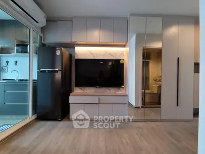 Modern living room with sleek cabinetry and built-in TV unit, featuring a stylish open kitchen layout.