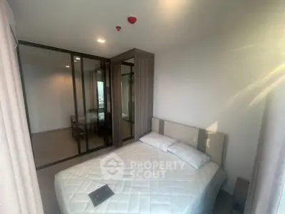 Modern bedroom with mirrored closet and natural light in a stylish apartment.
