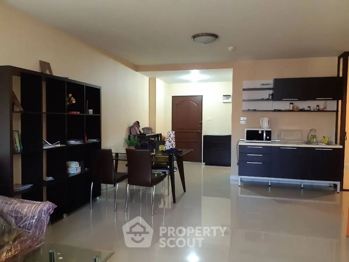 Modern open-plan living room with sleek kitchen and dining area, featuring contemporary furniture and glossy flooring.