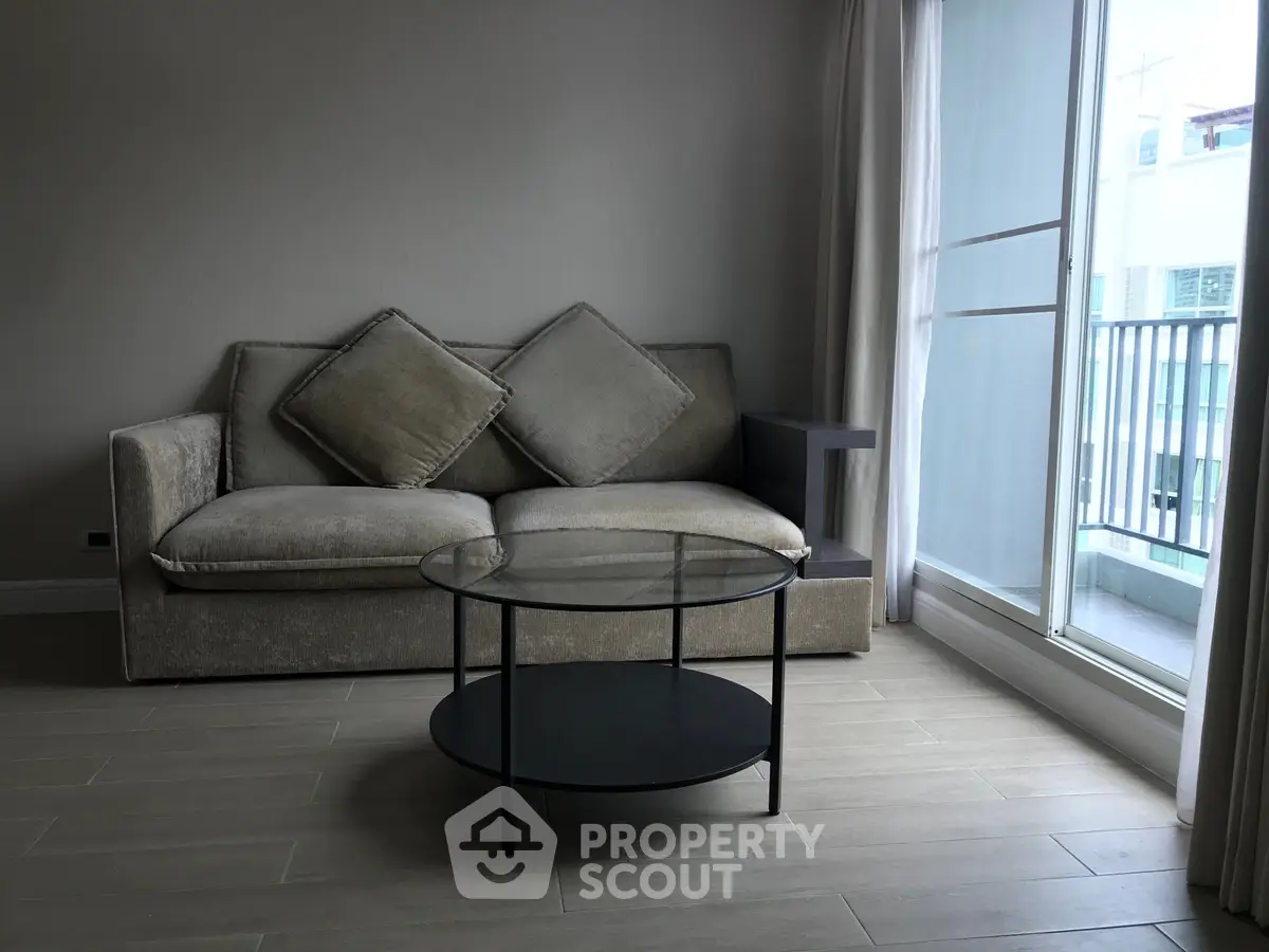 Modern living room with stylish sofa and glass coffee table near balcony