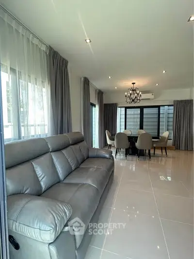 Spacious modern living room with elegant dining area and luxurious leather sofa.