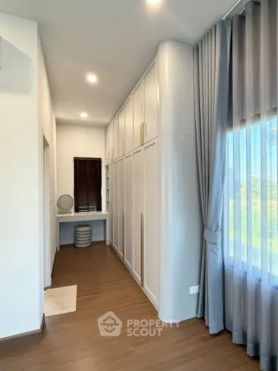 Spacious modern bedroom with elegant built-in wardrobes and large window view.