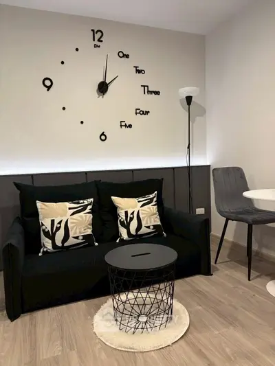 Modern living room with stylish black sofa, unique wall clock, and elegant decor