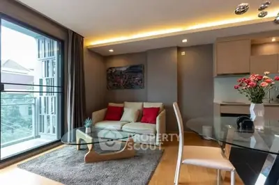 Modern living room with stylish decor and open kitchen layout, featuring large windows and cozy seating area.