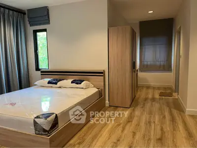 Modern bedroom with wooden flooring and large window in stylish apartment