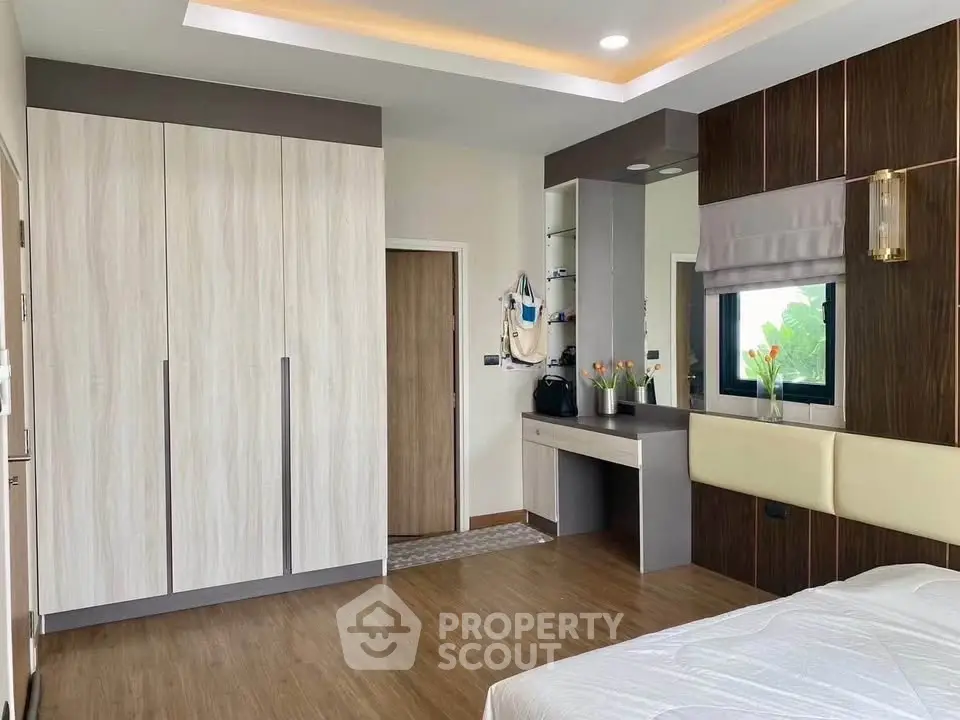 Modern bedroom with sleek wardrobe and stylish decor, featuring a cozy ambiance and elegant wooden flooring.