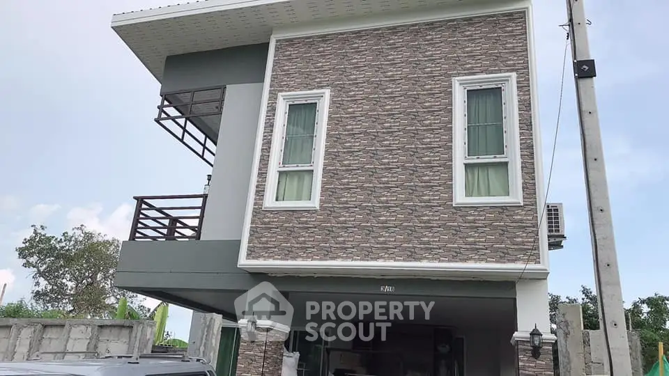 Modern two-story house with stone facade and balcony, showcasing contemporary architecture.