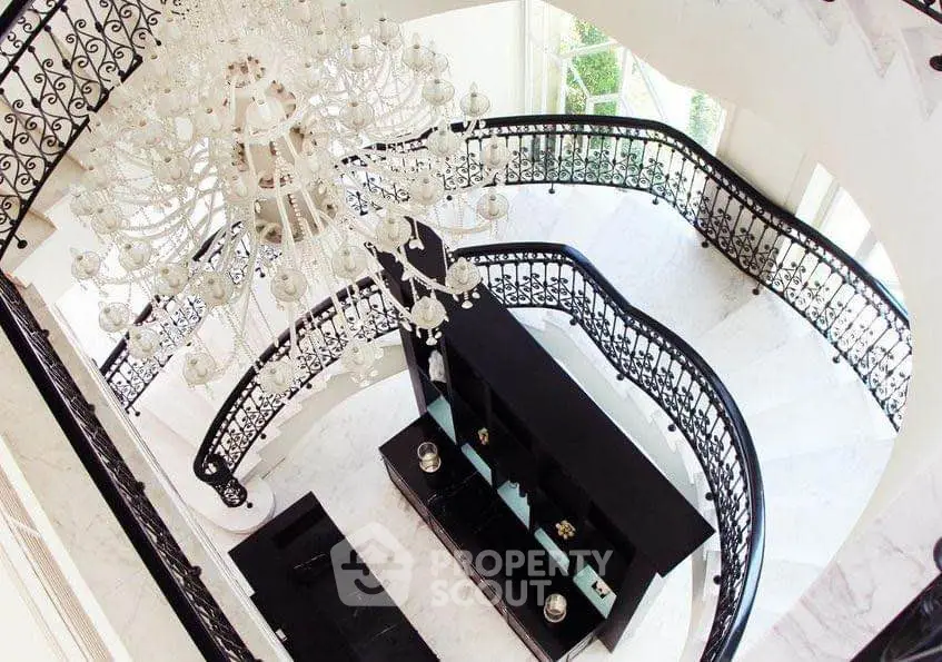 Luxurious spiral staircase with elegant chandelier in grand entrance foyer