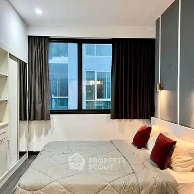 Modern bedroom with large window and stylish decor in urban apartment.