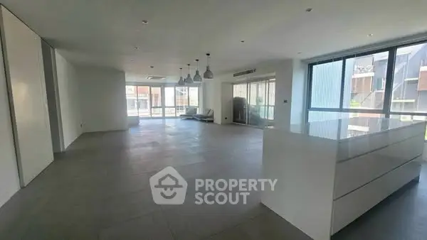 Spacious modern living room with large windows and open layout, perfect for urban living.