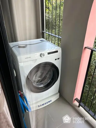 Compact balcony with Samsung washing machine and greenery view.