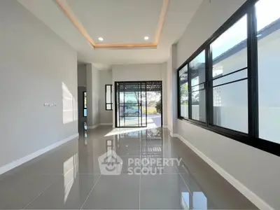 Spacious modern living room with large windows and glossy tiled floors, offering abundant natural light.