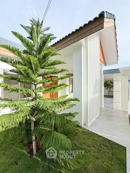 Modern minimalist house exterior with lush greenery and sleek architectural design.
