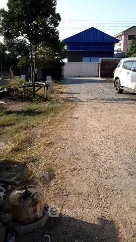Spacious outdoor area with gravel path and parked car, ideal for development.