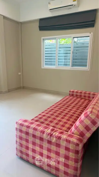Spacious living room with checkered sofa and large window, perfect for relaxation and natural light.