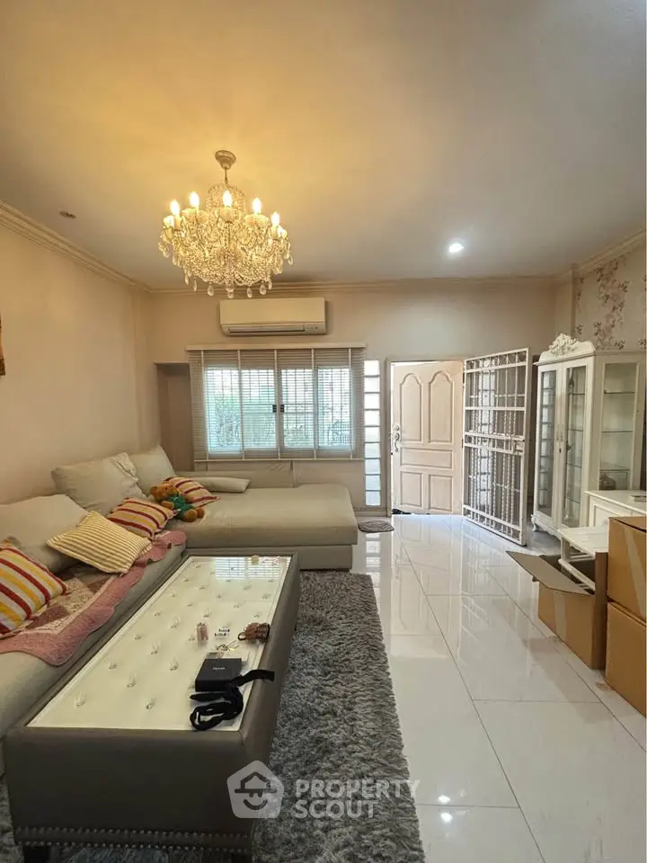 Elegant living room with chandelier, plush sofa, and glossy tile flooring, perfect for modern family living.