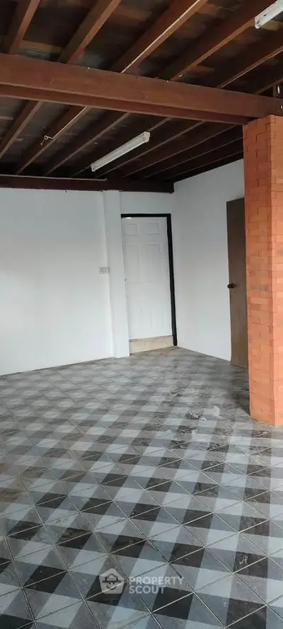 Spacious interior with tiled flooring and exposed wooden beams, ideal for customization.