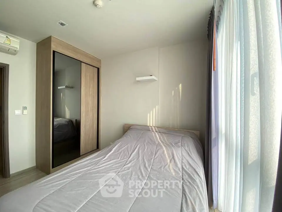 Bright and cozy bedroom with large window and modern wardrobe in a stylish apartment.