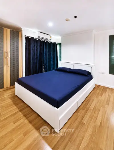 Spacious bedroom with wooden flooring and modern furnishings