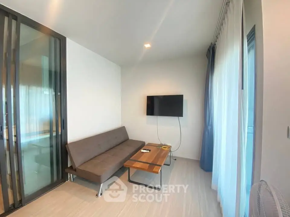 Modern living room with sleek sofa and wall-mounted TV, featuring large windows and elegant decor.