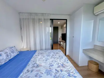 Bright and airy bedroom with floral bedding, large window, and modern decor.