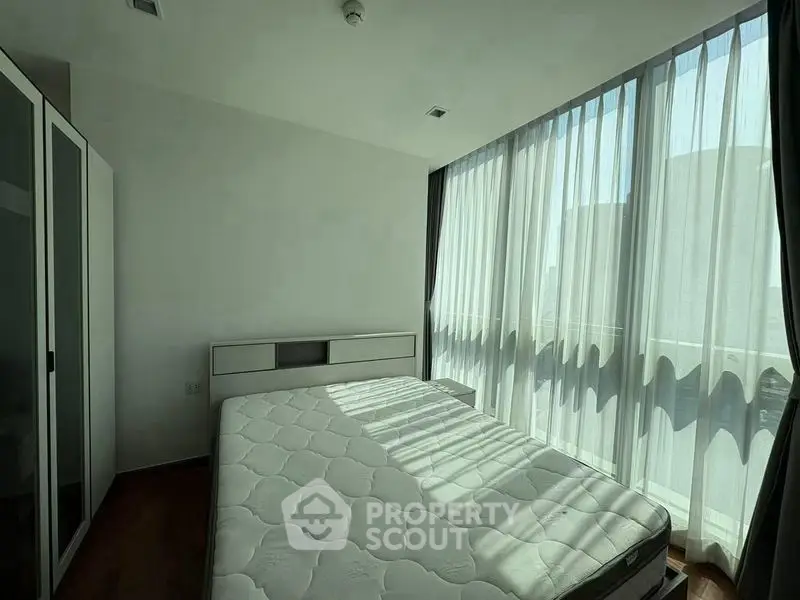 Bright bedroom with large windows and modern furnishings in a stylish apartment.
