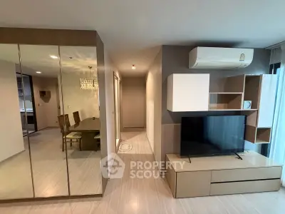 Modern living room with sleek design, mirrored wall, and dining area in a stylish apartment.