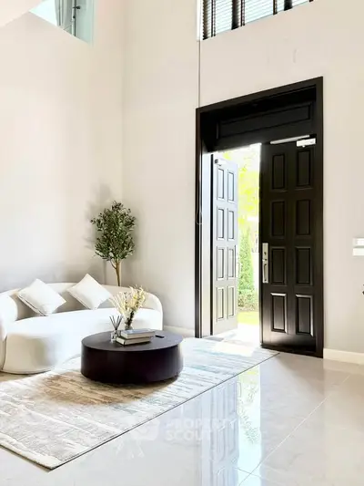Elegant living room with open door, modern furniture, and natural light.