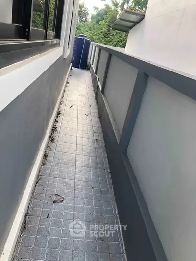 Narrow exterior walkway with modern railing and tiled flooring