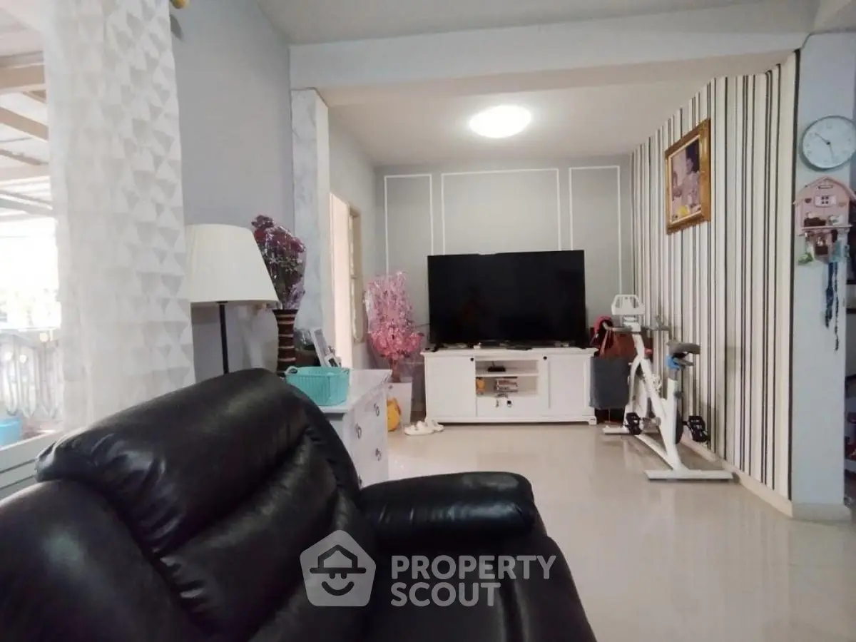 Spacious living room with modern decor and large TV, perfect for relaxation.