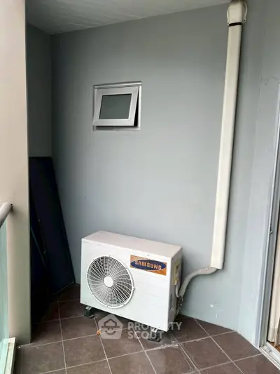 Compact balcony with air conditioning unit and small window, ideal for urban living spaces.