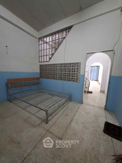 Spacious room with metal bed frame and unique architectural window design