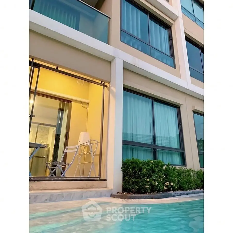Modern apartment building with poolside view and glass balconies, perfect for luxury living.