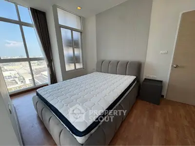 Spacious bedroom with large windows offering city views and modern furnishings.