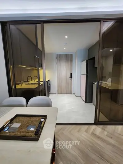 Modern kitchen with sleek design and closed layout, featuring stylish cabinetry and dining area.