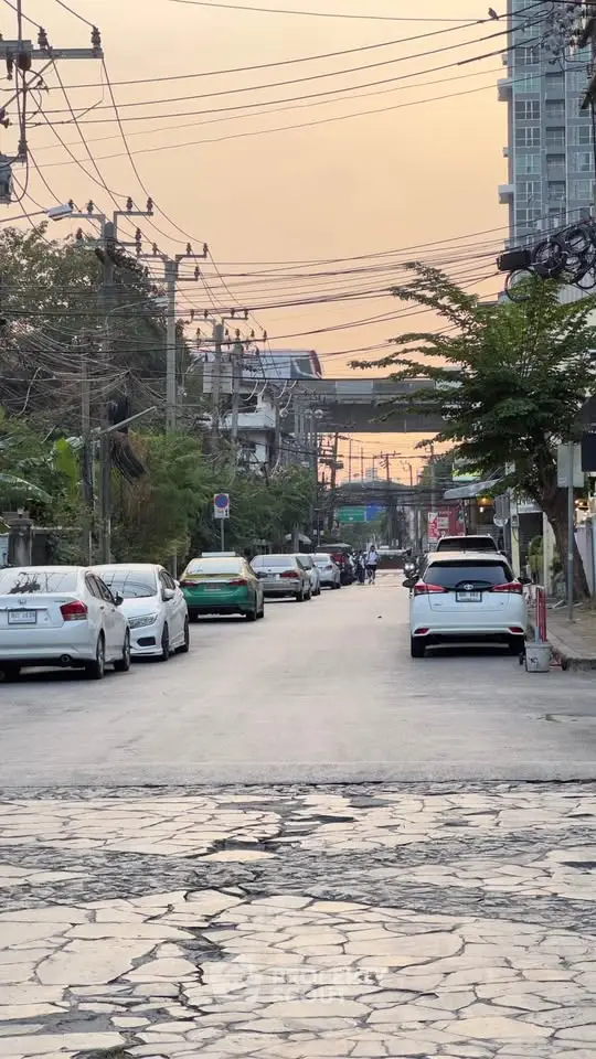 Urban street view with parked cars and residential buildings at sunset.