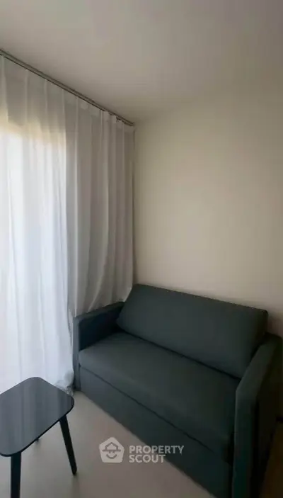 Cozy living room with modern sofa and sheer curtains, perfect for relaxation.