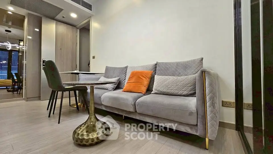 Modern living room with stylish gray sofa and chic dining area in open layout apartment.