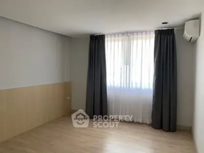 Spacious empty room with large window and air conditioning, perfect for customization.