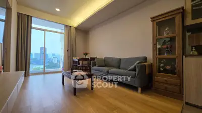 Spacious living room with city view, wooden flooring, and elegant furniture in modern apartment.