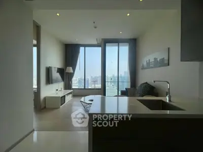 Modern living room with city view, open layout, and sleek furnishings in high-rise apartment.