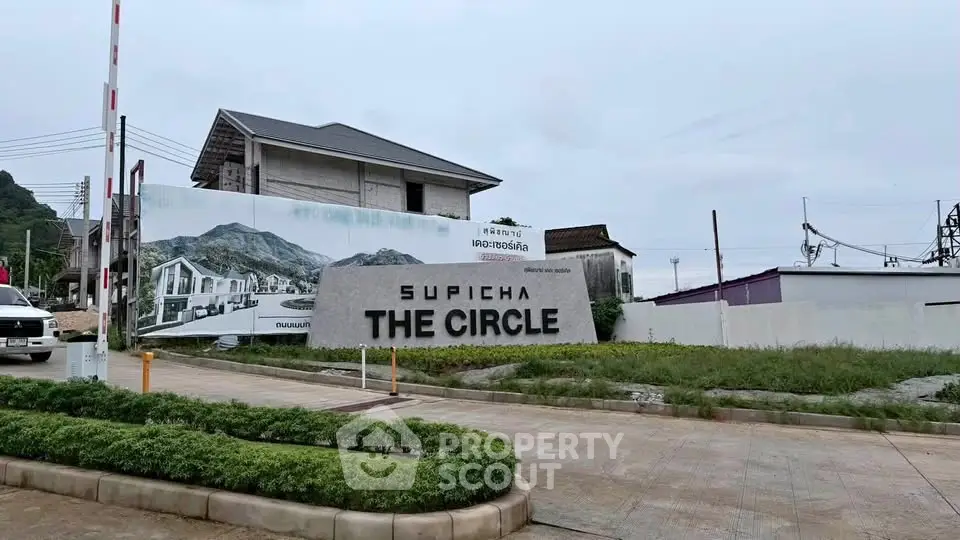 Modern residential development entrance with landscaped greenery and contemporary signage.