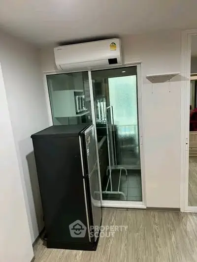 Modern apartment interior with sleek black fridge and air conditioning unit.