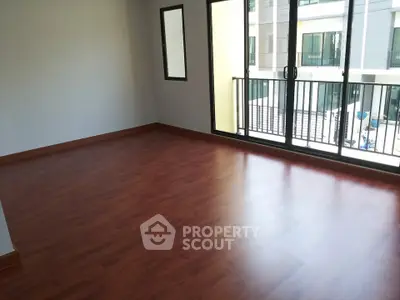 Spacious empty room with wooden flooring and large windows in modern apartment.