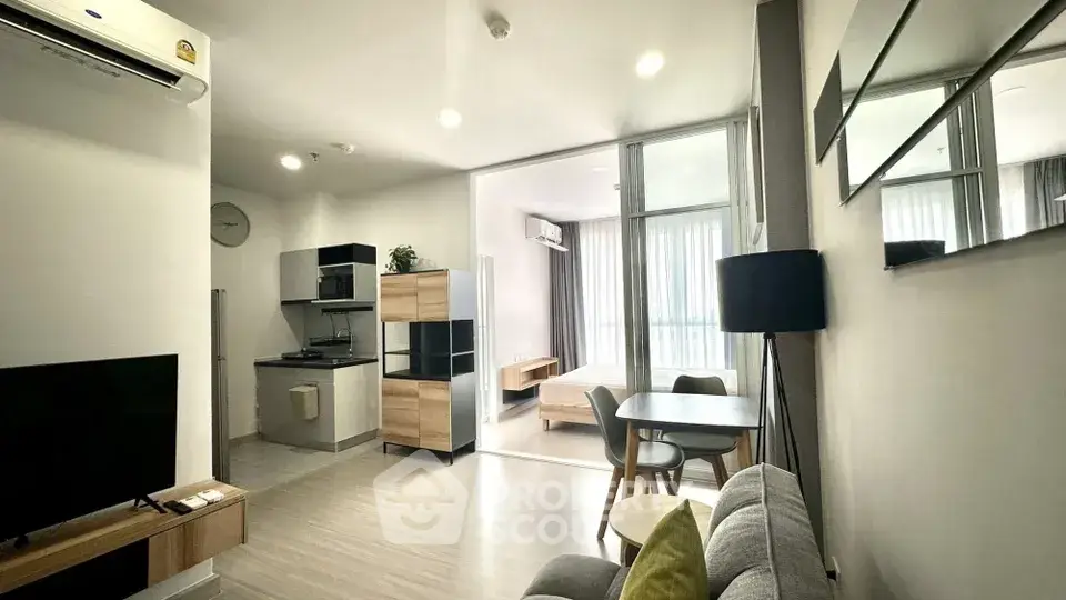 Modern open-plan living room with kitchen and dining area, featuring sleek furniture and natural light.
