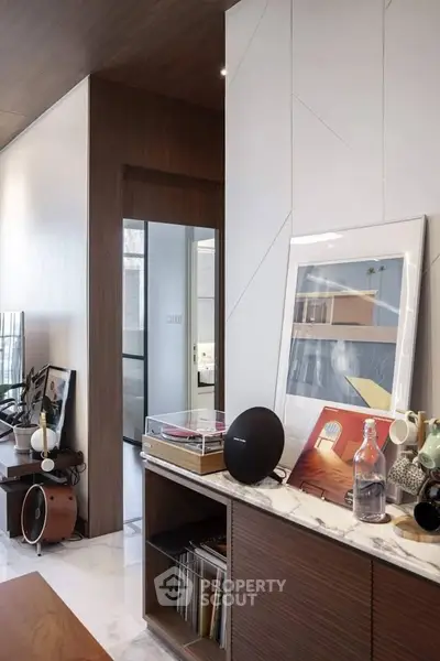 Stylish modern living room with elegant decor and marble accents, featuring a sleek audio system and contemporary artwork.