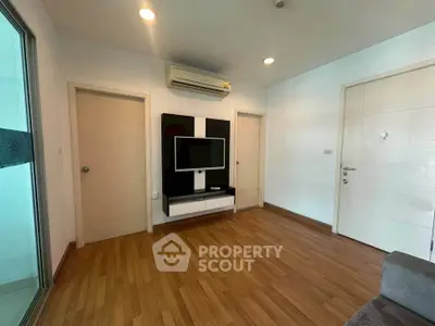 Modern living room with wooden flooring and sleek TV setup in a stylish apartment.