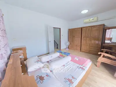 Cozy bedroom with wooden furniture and playful bedding, featuring ample storage and natural light.