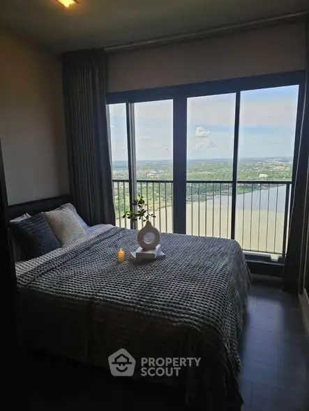 Luxurious bedroom with stunning river view from floor-to-ceiling windows, featuring elegant decor and cozy ambiance.