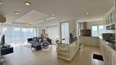 Spacious open-plan living room and kitchen with city view and modern decor.